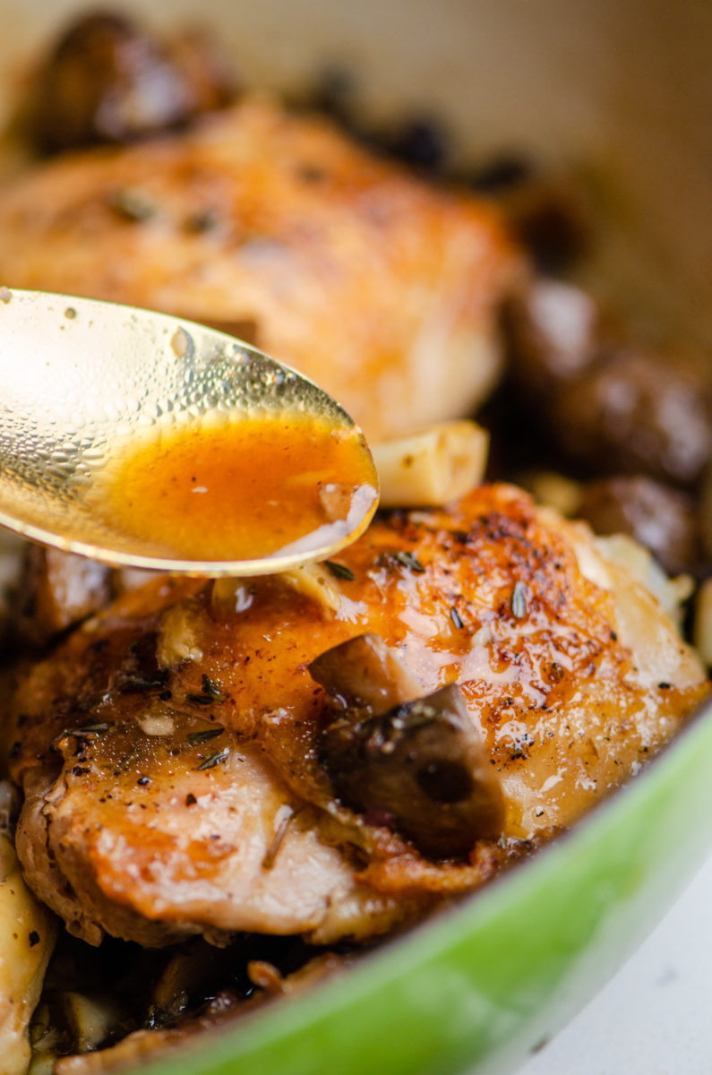 Gravy is spooned over top baked chicken with mushrooms.
