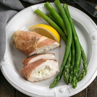 Boursin stuffed chicken breasts on a plate next to asparagus.