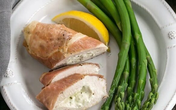 Boursin stuffed chicken breasts on a plate next to asparagus.