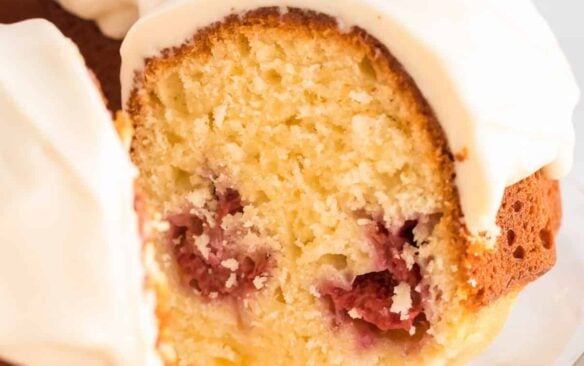 A glazed raspberry lemon bundt cake with a slice missing.