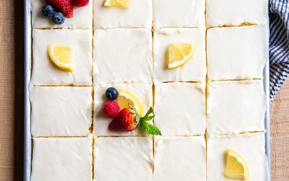 Top view of a lemon sheet cake cut into squares.