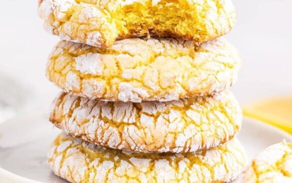 A stack of lemon cake mix cookies with the top cookie missing a bite.