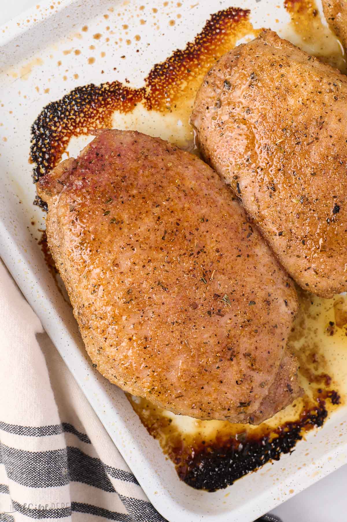 close up image of juicy baked pork chop on white pan