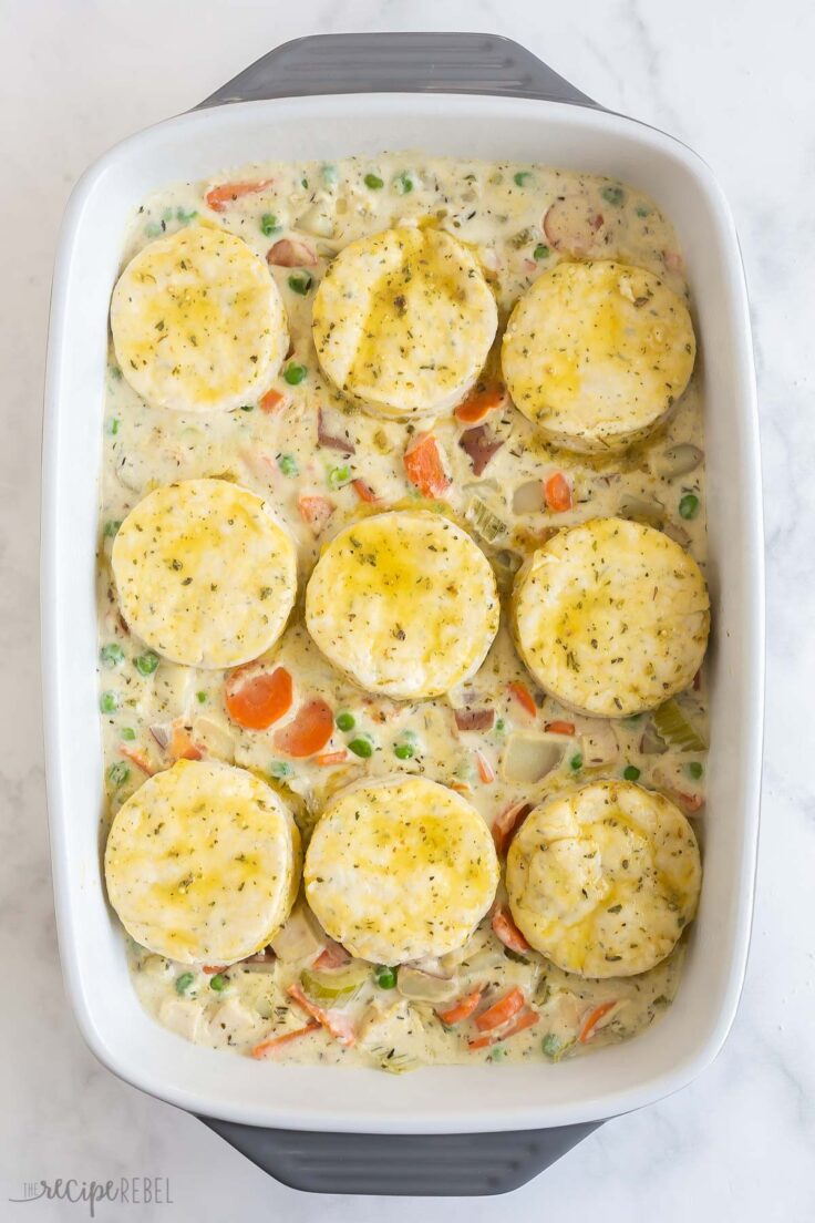 biscuits on top of chicken pot pie filling in white baking dish
