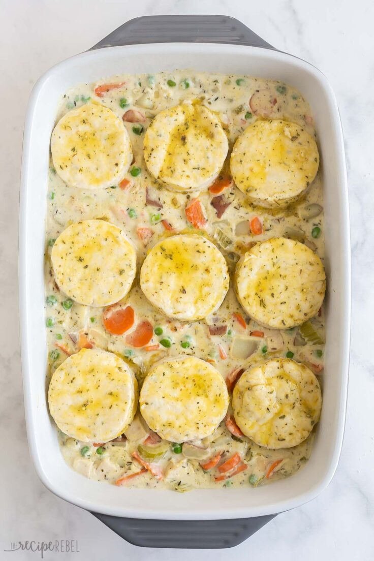 biscuits on top of chicken pot pie filling in white baking dish