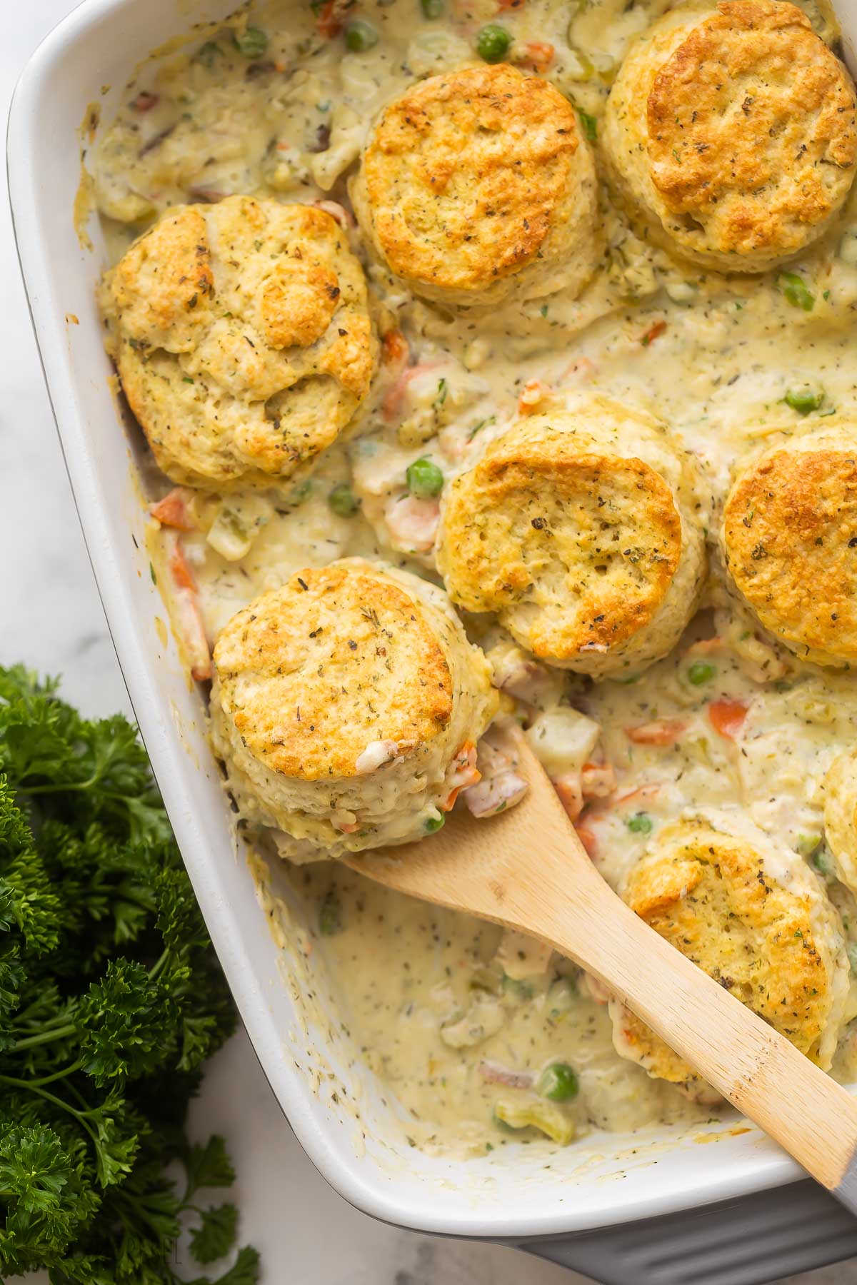wooden spoon in chicken pot pie casserole with biscuits on top