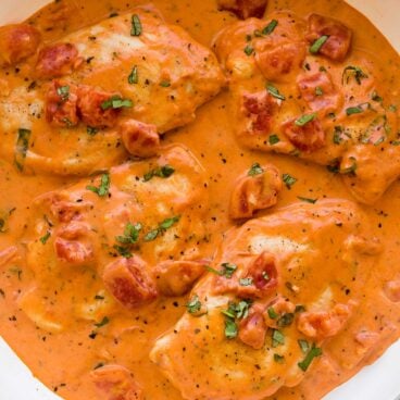 close up overhead image of tomato basil chicken breasts in white skillet