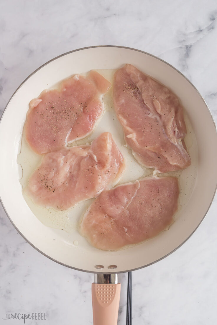 chicken breasts browning in white skillet