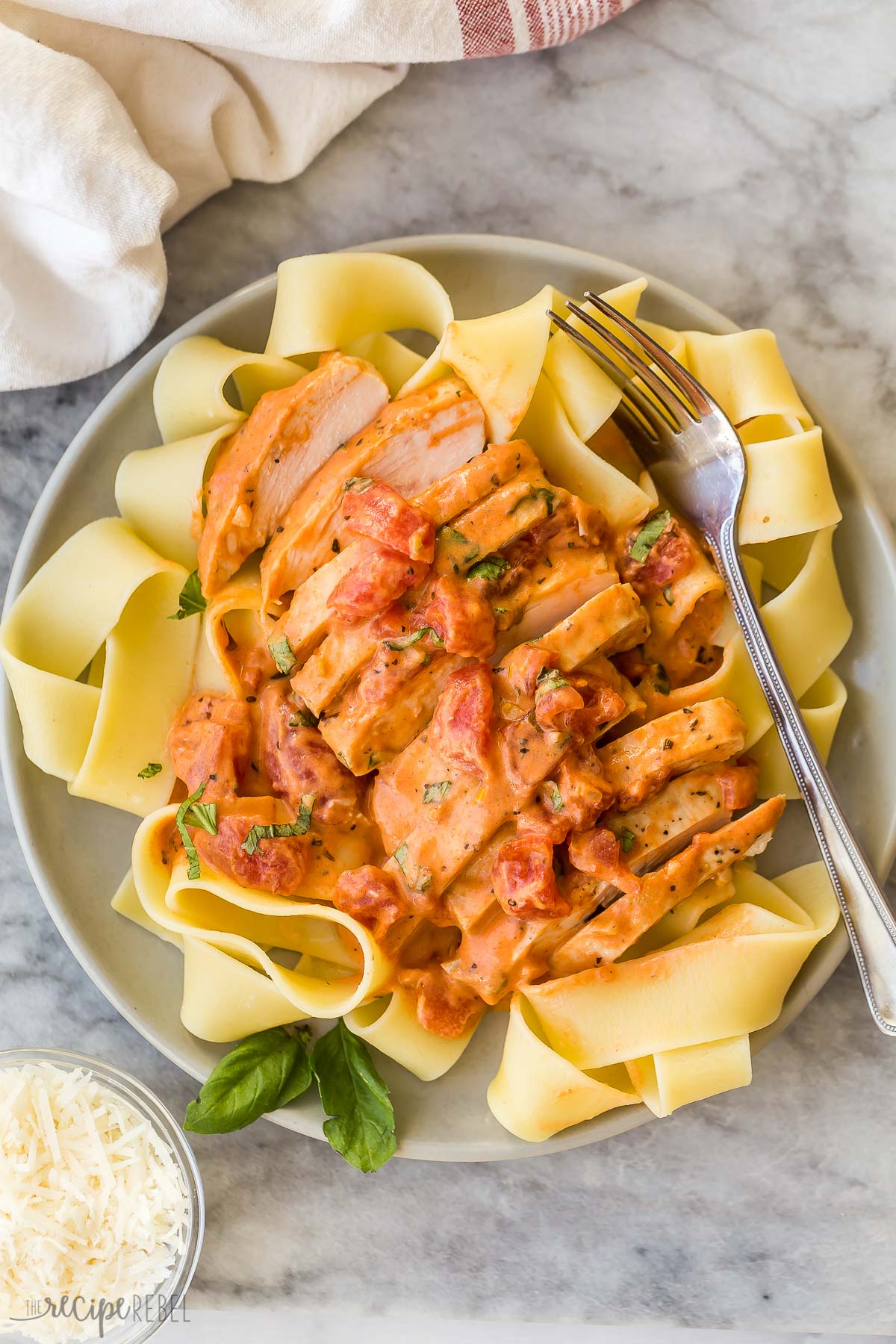 overhead image of creamy tomato basil chicken breasts on pasta
