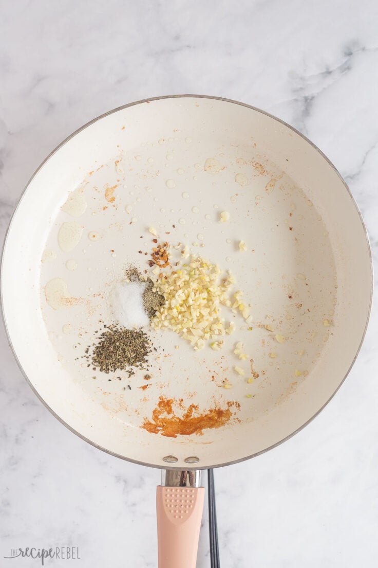 garlic and spices toasting in white skillet