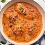 square image of four chicken breasts in tomato basil sauce in a white skillet.