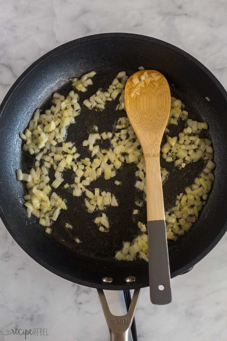 onions sauteed in skillet with wooden spoon