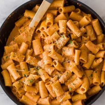 overhead image of rigatoni pasta with tomato sauce in skillet with wooden spoon