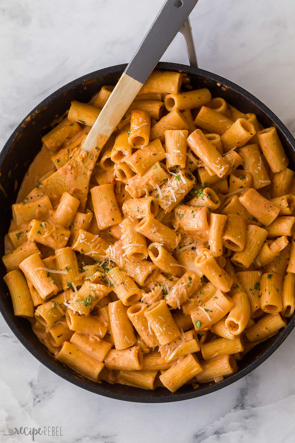 overhead image of rigatoni pasta with tomato sauce in skillet with wooden spoon