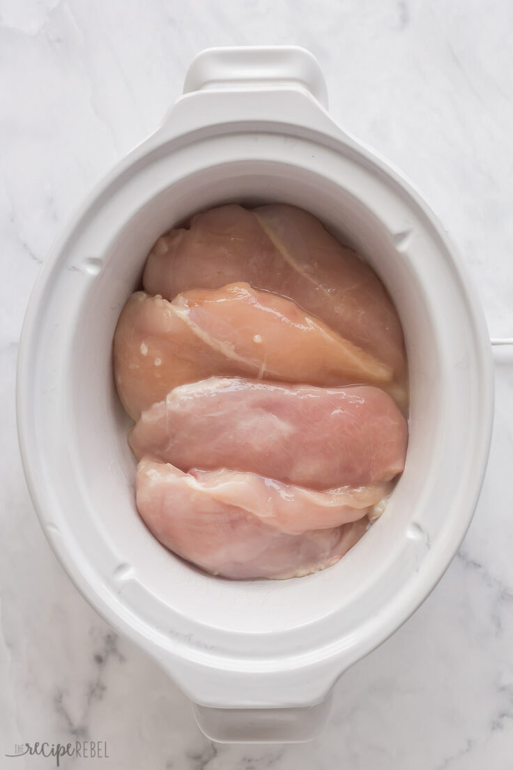 uncooked chicken breasts in white slow cooker