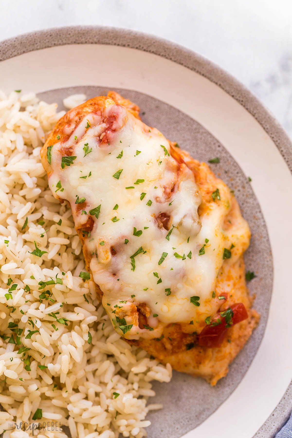close up image of one salsa chicken breast on grey plate with rice