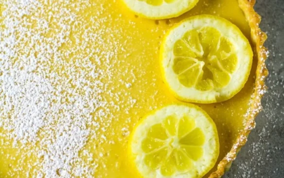 Top view of a bright yellow lemon tart garnished with lemon slices.