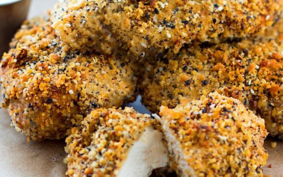 Everything bagel chicken breasts piled on a plate.