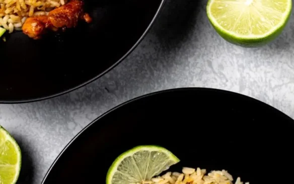 Honey lime chicken served over rice on black plates.
