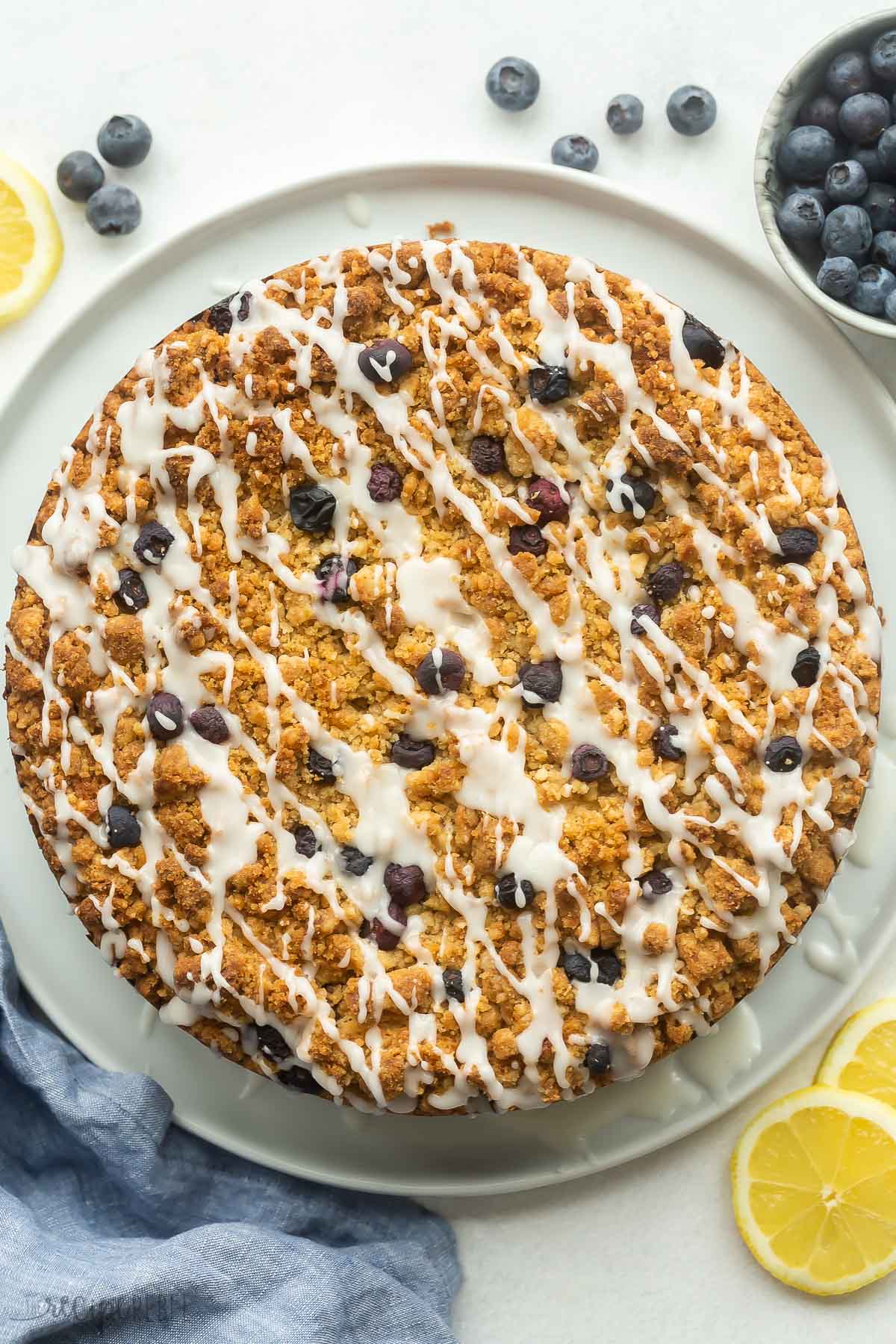 overhead image of whole lemon blueberry coffee cake with glaze drizzled over