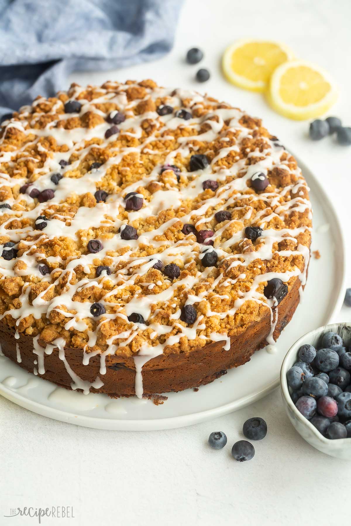 whole lemon blueberry coffee cake on a white plate with glaze