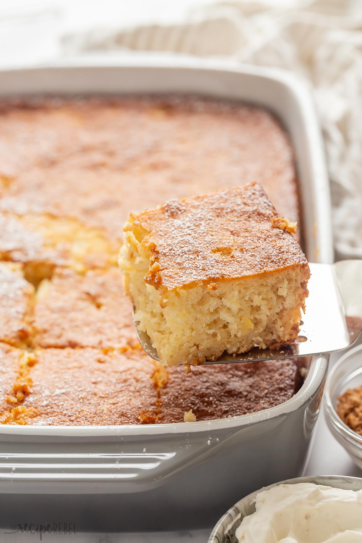 metal spatula scooping piece of pineapple cake from the baking pan