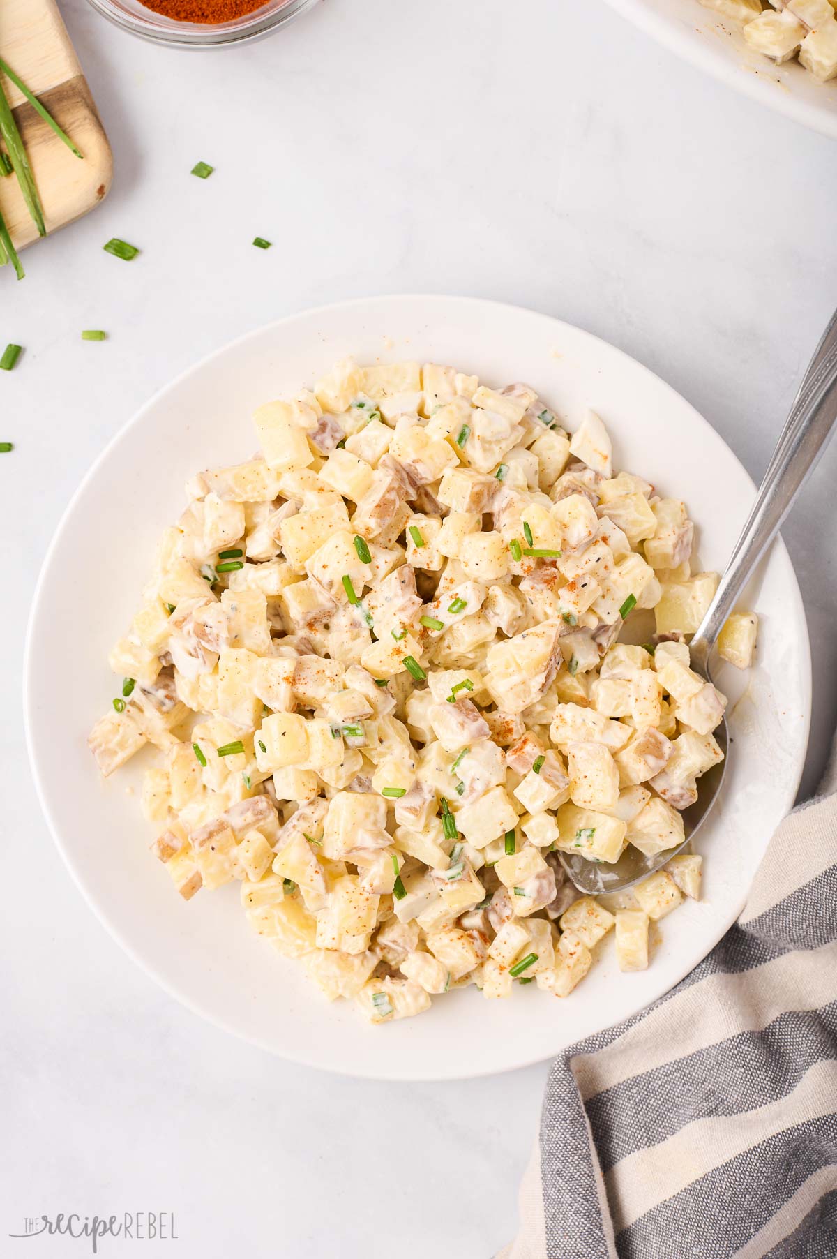 overhead image of potato salad in a white bowl with a spoon