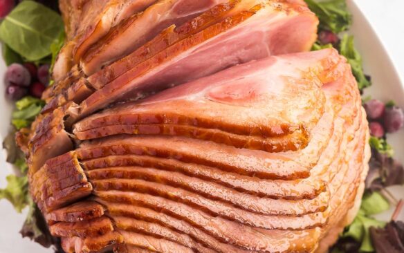 glazed spiral ham on a white platter with greens'