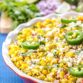 Mexican street corn salad in a red bowl garnished with green jalapeno slices.