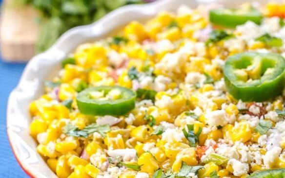 Mexican street corn salad in a red bowl garnished with green jalapeno slices.