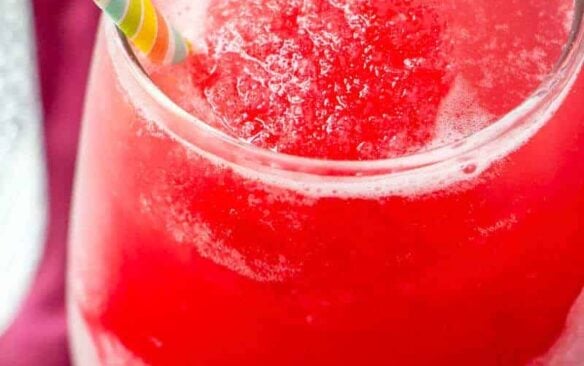 A glass of bright red rhubarb slush with a straw.