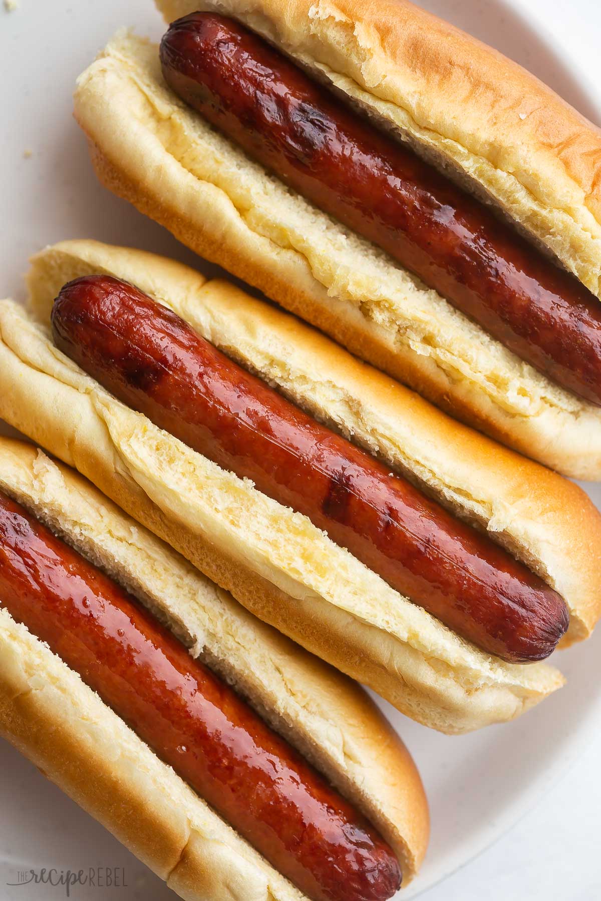close up overhead image of air fryer hot dogs in buns on plate