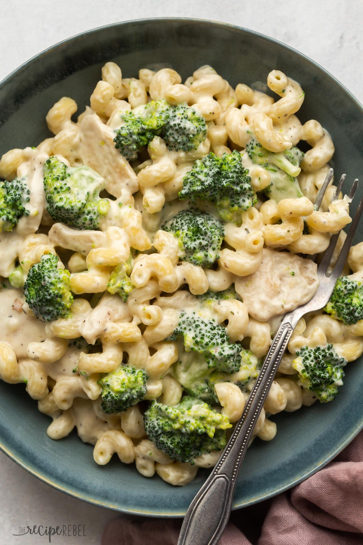 close up overhead image of chicken broccoli alfredo in blue bowl with fork