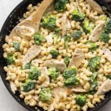 overhead image of chicken alfredo pasta in skillet with wooden spoon