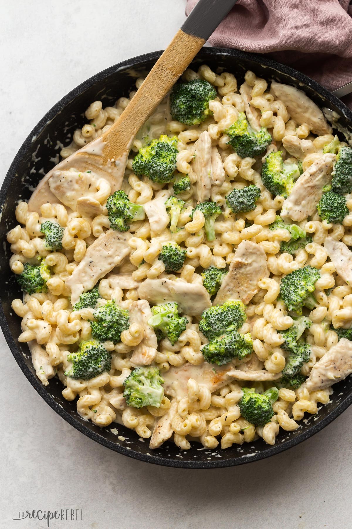 overhead image of chicken alfredo pasta in skillet with wooden spoon