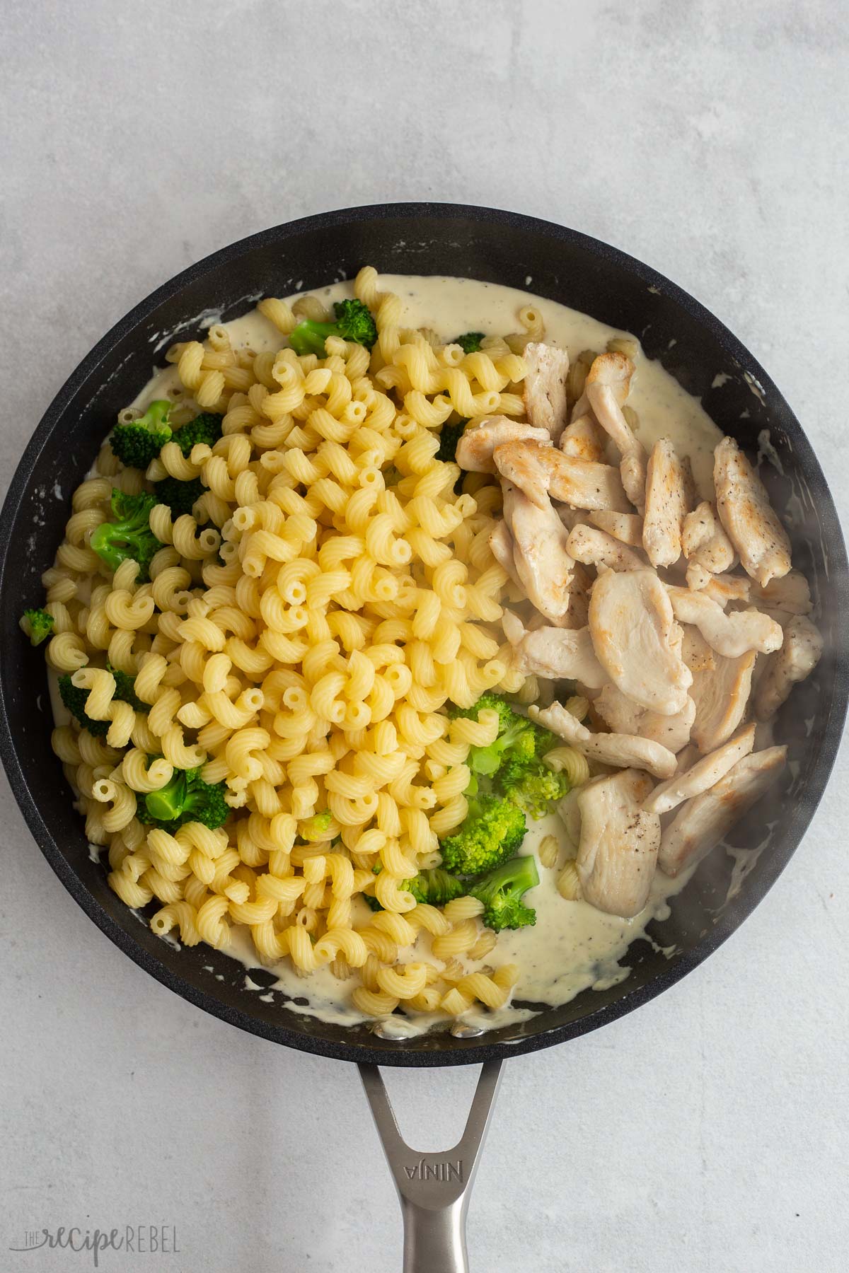 broccoli pasta and chicken added to alfredo sauce in skillet