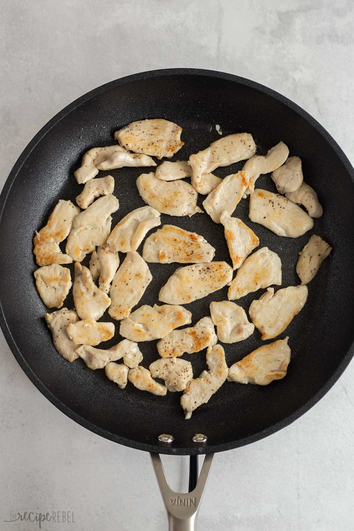 strips of chicken breast being browned in a skillet
