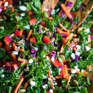 Chopped kale salad in a wooden bowl with a wooden salad spoon.