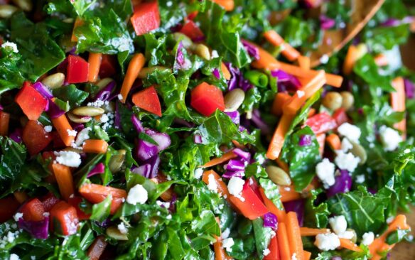 Chopped kale salad in a wooden bowl with a wooden salad spoon.