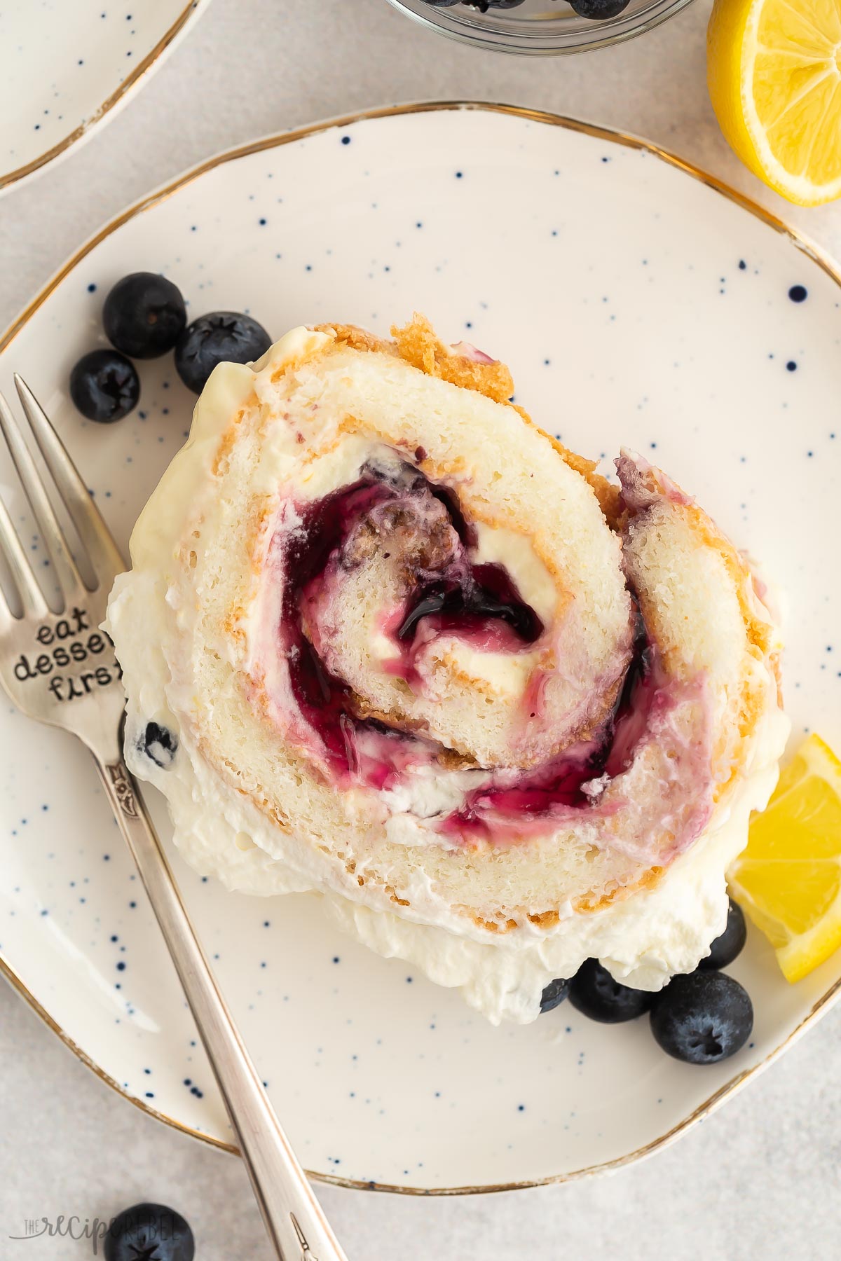 overhead image of a slice of lemon blueberry cake roll on white plate