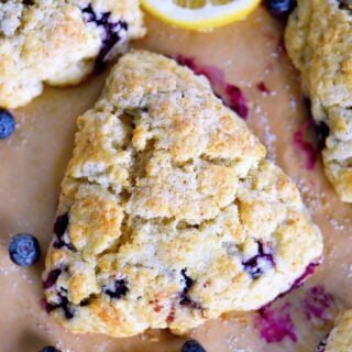 Blueberry scones surrounded by lemon slices and fresh berries.
