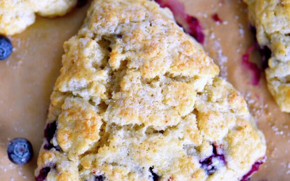 Blueberry scones surrounded by lemon slices and fresh berries.