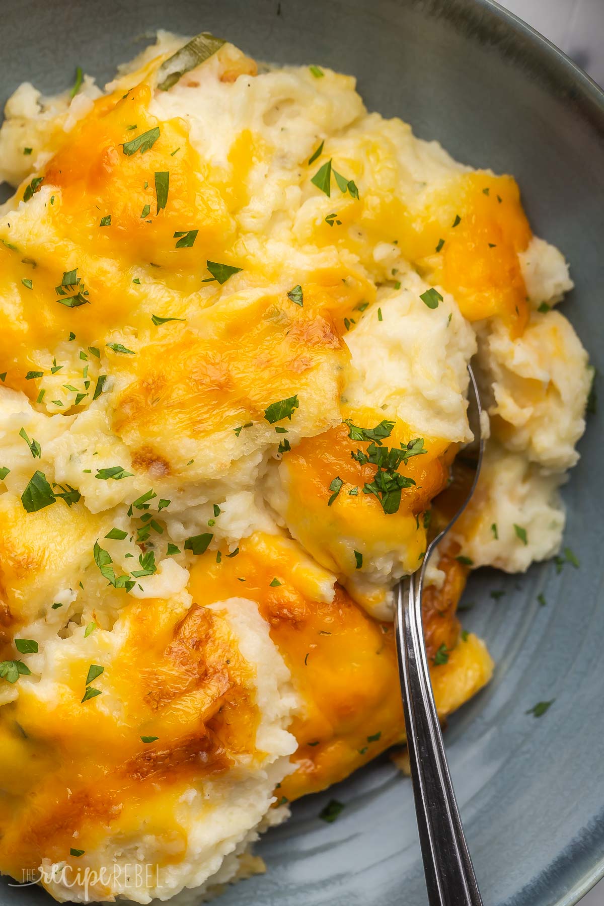 close up image of make ahead mashed potatoes in blue bowl with spoon.