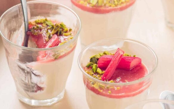 Glasses of garnished rhubarb panna cotta.