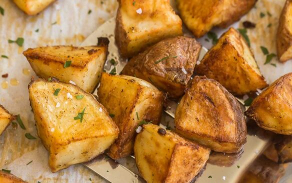 metal ladle scooping roasted red potatoes from baking sheet