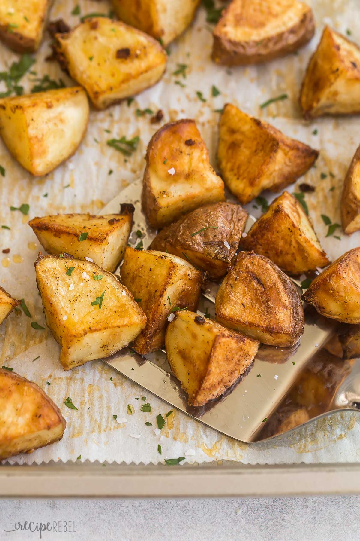 metal ladle scooping roasted red potatoes from baking sheet