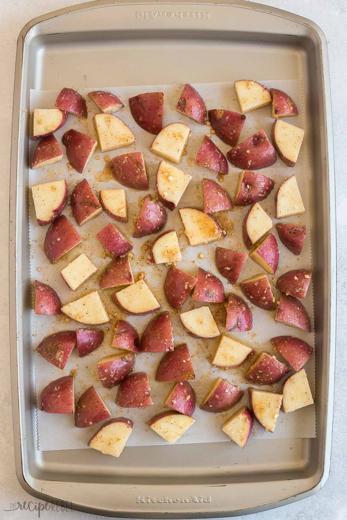 seasoned potatoes on baking sheet with parchment paper