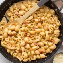 overhead image of sun dried tomato pasta in skillet with wooden spoon