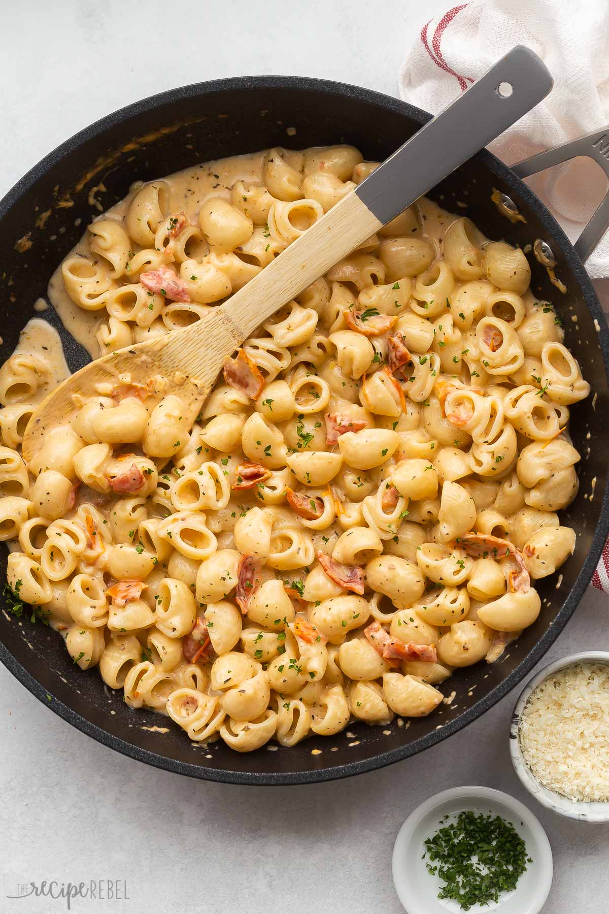 overhead image of sun dried tomato pasta in skillet with wooden spoon