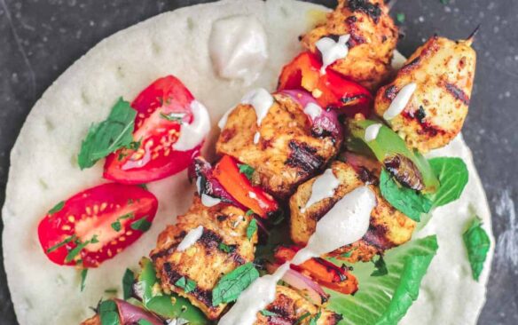 overhead of grilled chicken kabobs on a white plate